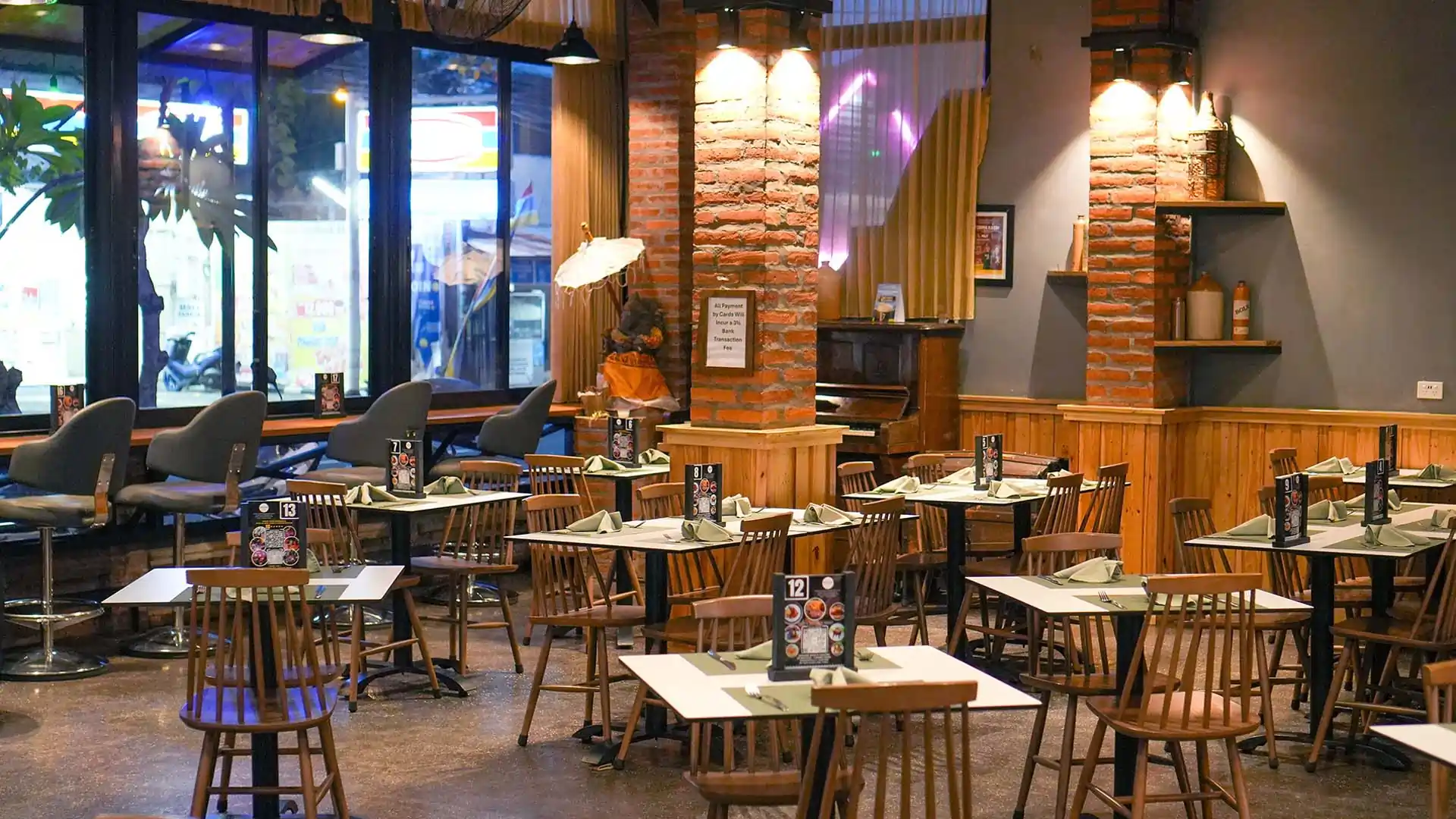 Cozy window-side dining tables with rustic brick columns at Rah Nah, a top restaurant in Lovina for evening meals.