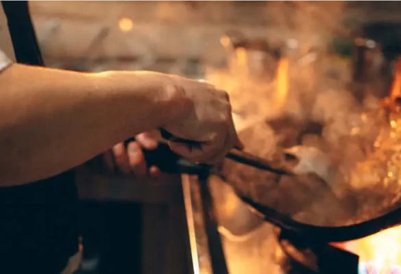 Chef preparing a fresh lunch or dinner dish with flames at Rah Nah Tapas Bar & Restaurant, a top dining spot in Lovina Bali.