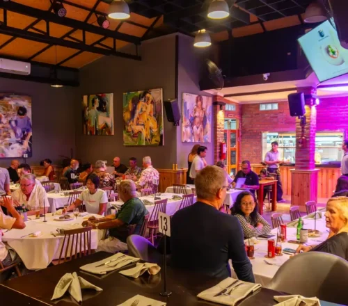 Rah Nah Tapas Bar and Restaurant in Lovina features a vibrant evening atmosphere, with guests enjoying dinner in a lively dining room surrounded by colorful modern art and warm lighting.